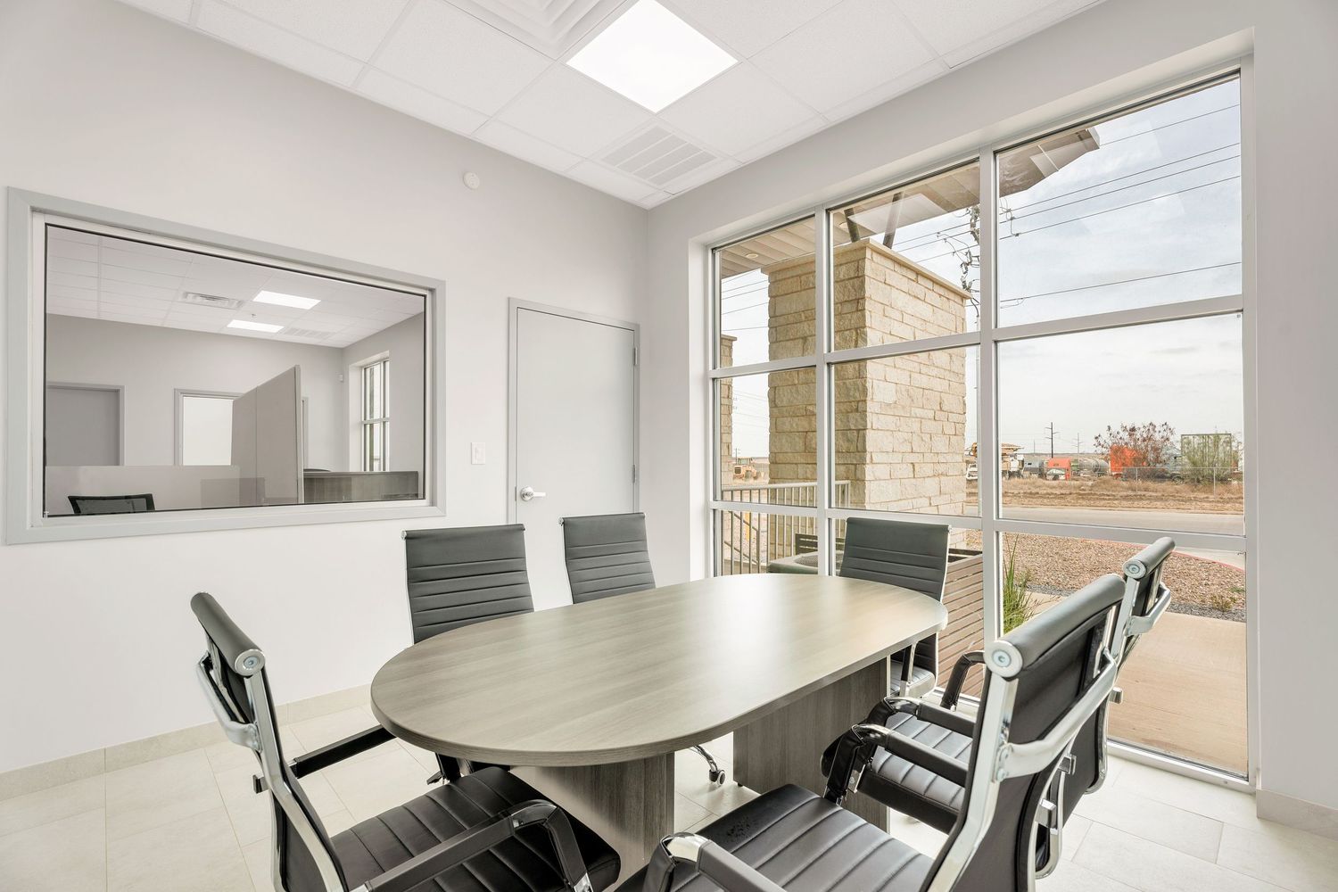 Modern white conference room with glass walls, sleek furniture, and natural lighting from large windows.