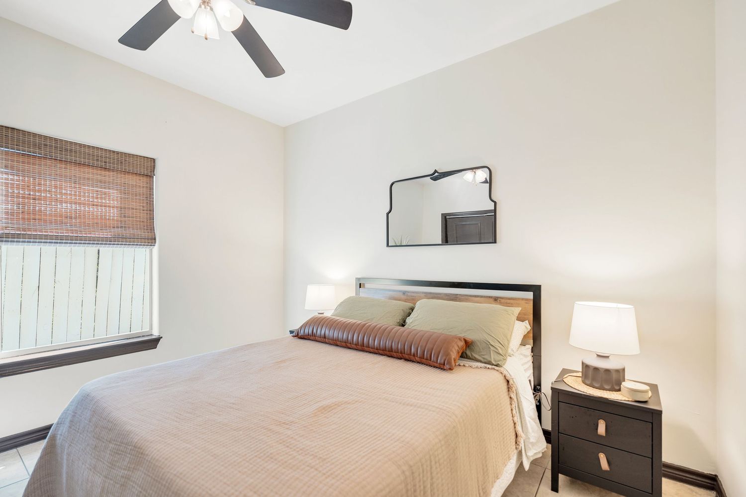 Cozy bedroom interior with bamboo window shades and contemporary furnishings.