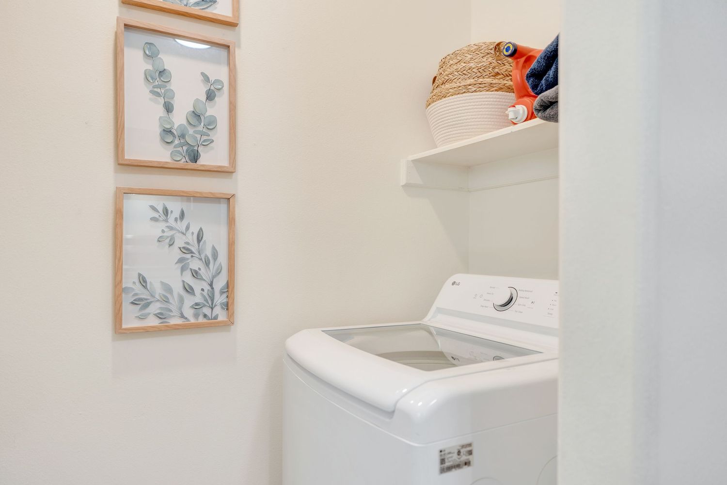 Clean white bathroom interior with framed botanical artwork and wall-mounted storage solutions.