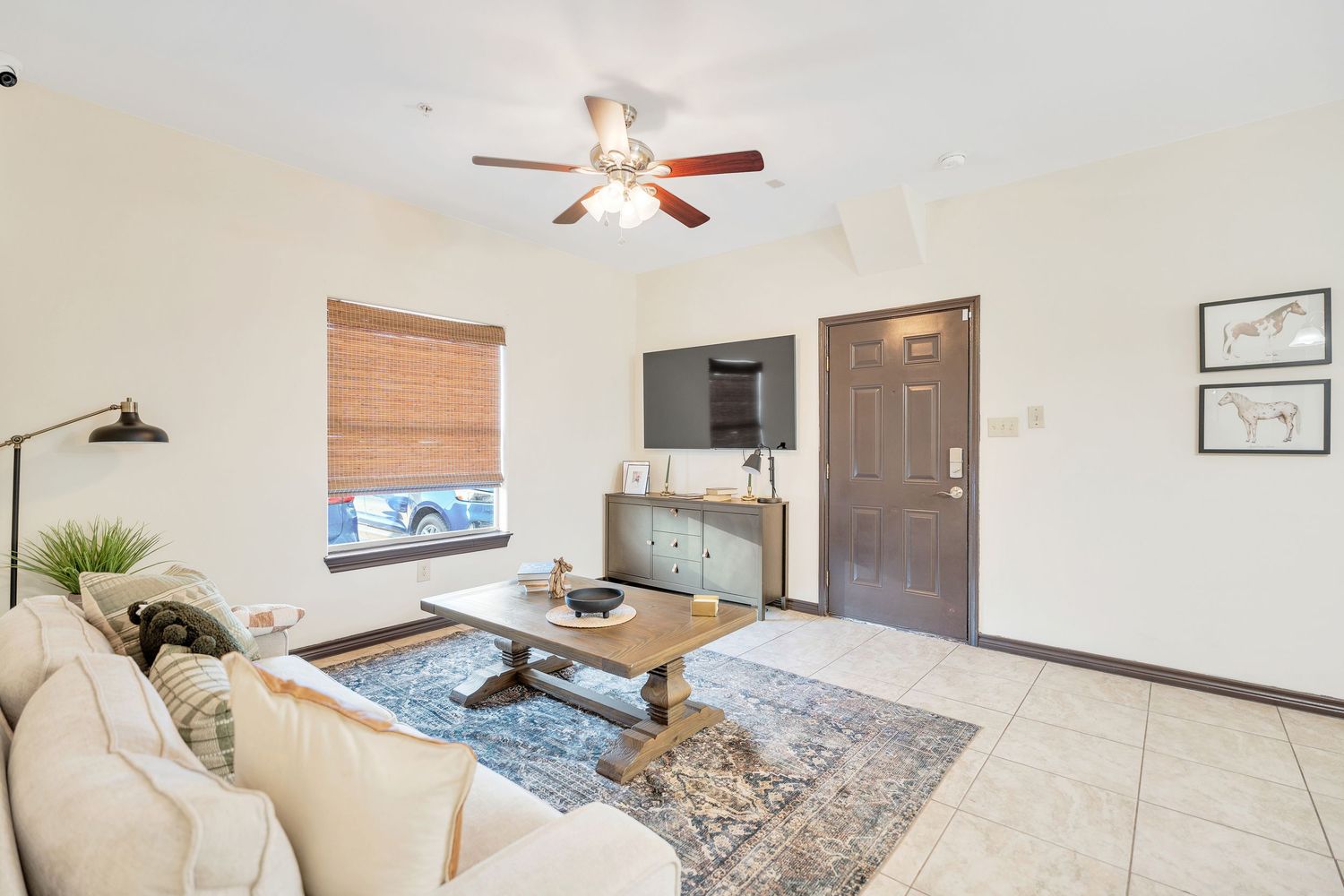 Modern bedroom with ceiling fan, wooden blinds, and coastal decor featuring a mounted longhorn skull on white walls.