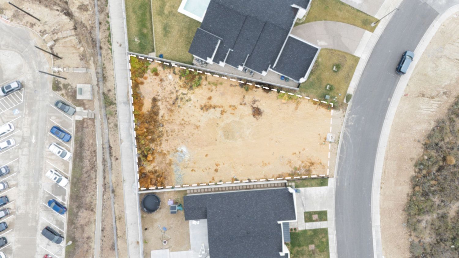 Aerial view of a winding road through desert terrain with scattered buildings and parking lots visible from above.
