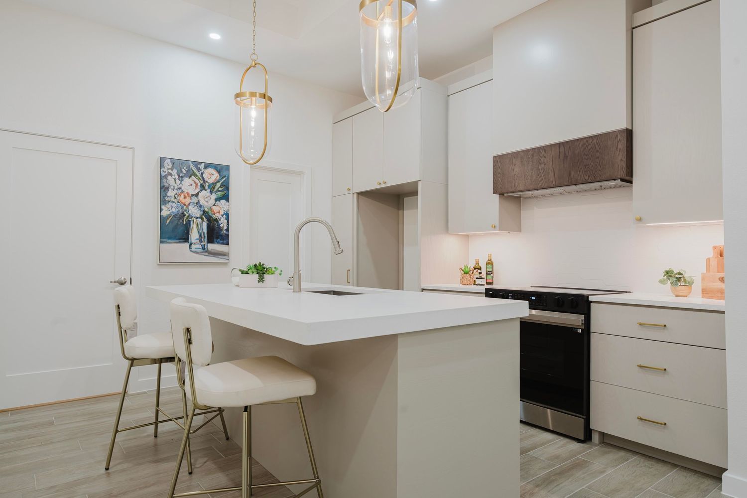 Contemporary kitchen featuring white cabinets, pendant lighting, and breakfast bar with modern stools.