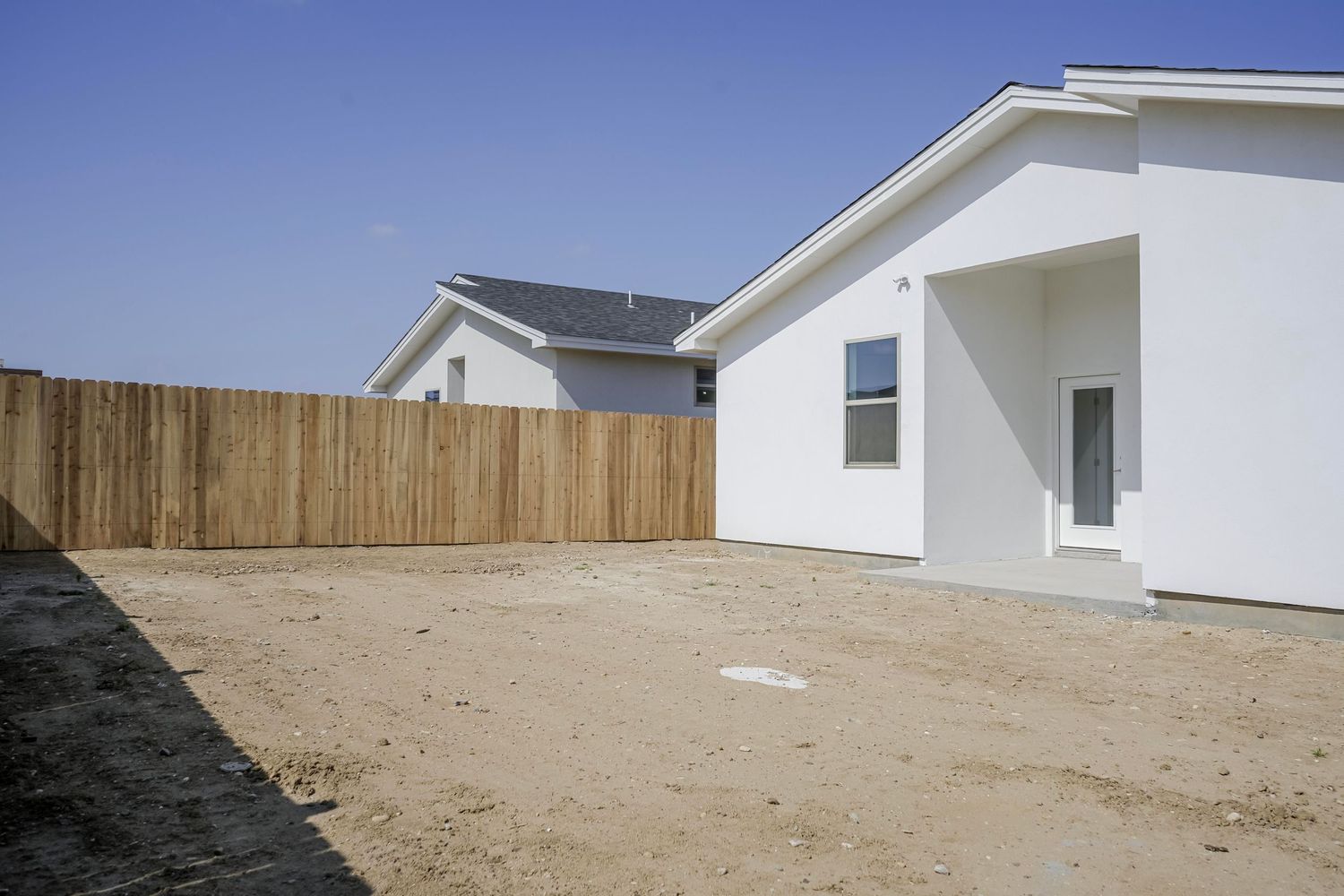 White residential homes with wooden fencing and unfinished dirt yards.