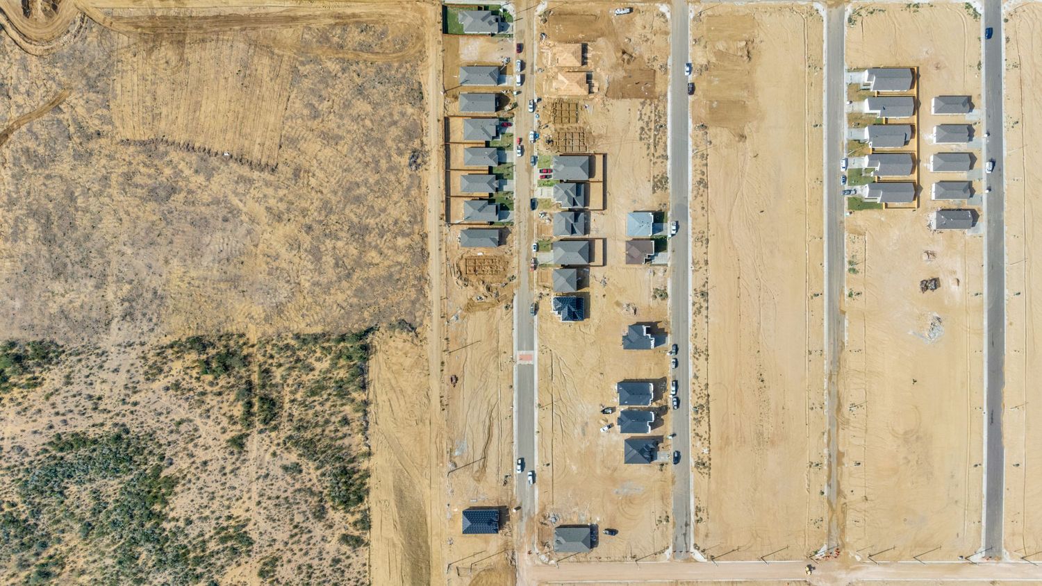 Aerial view of desert terrain with scattered mobile homes and buildings arranged in a grid pattern.