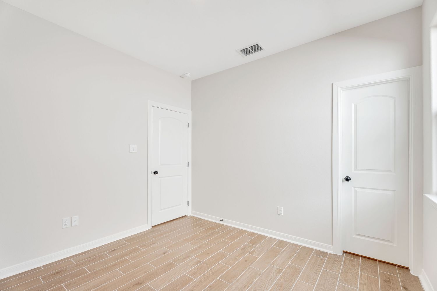 Empty white interior room with light hardwood flooring and multiple doorways visible in panoramic view.