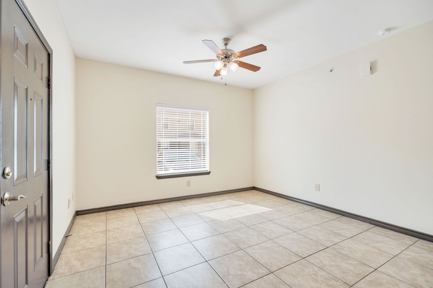 Empty room with tiled flooring and white walls features recessed lighting and a ceiling fan.