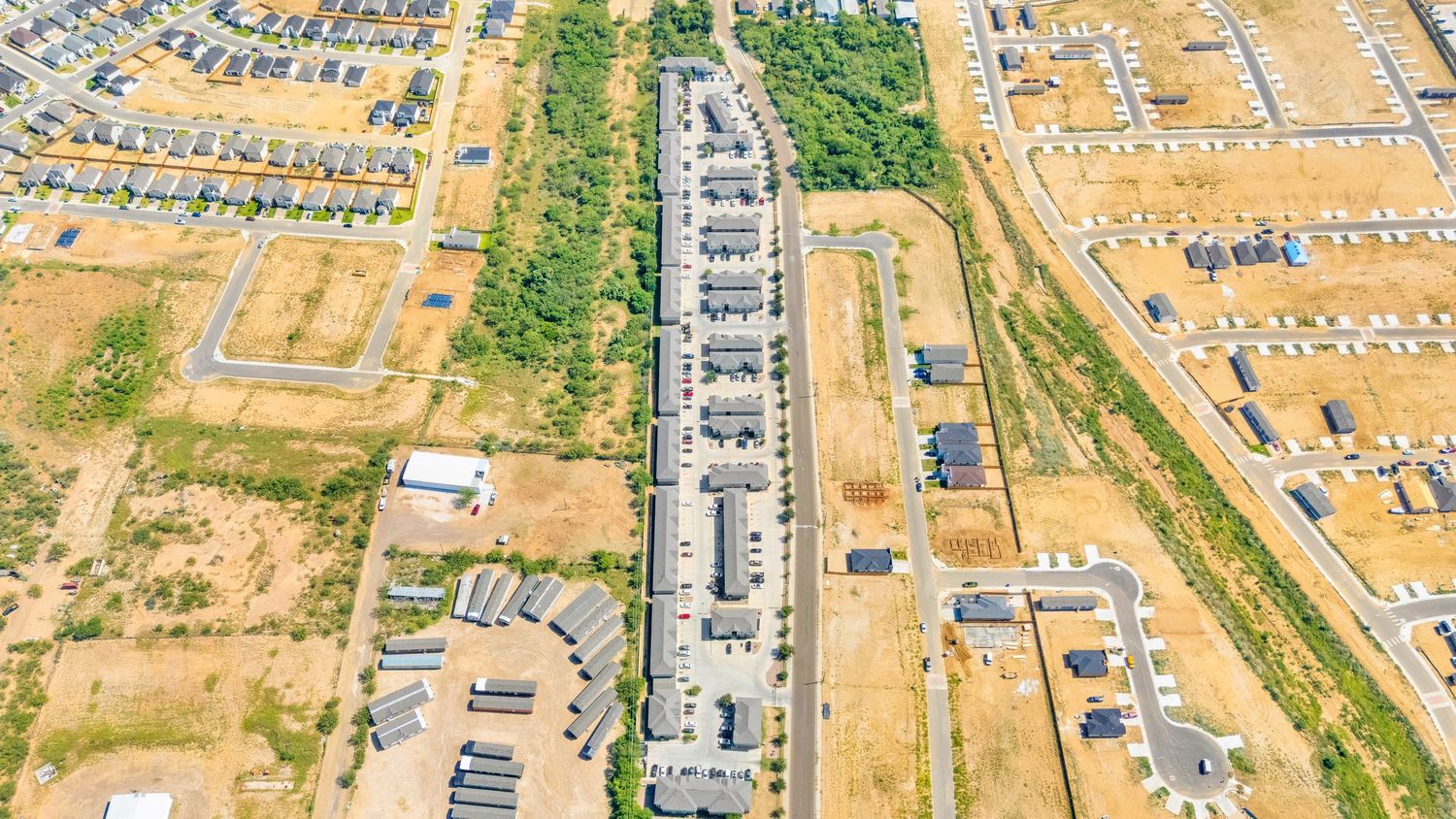 Aerial panoramic view of a residential development showing roads and housing plots in various stages of construction.