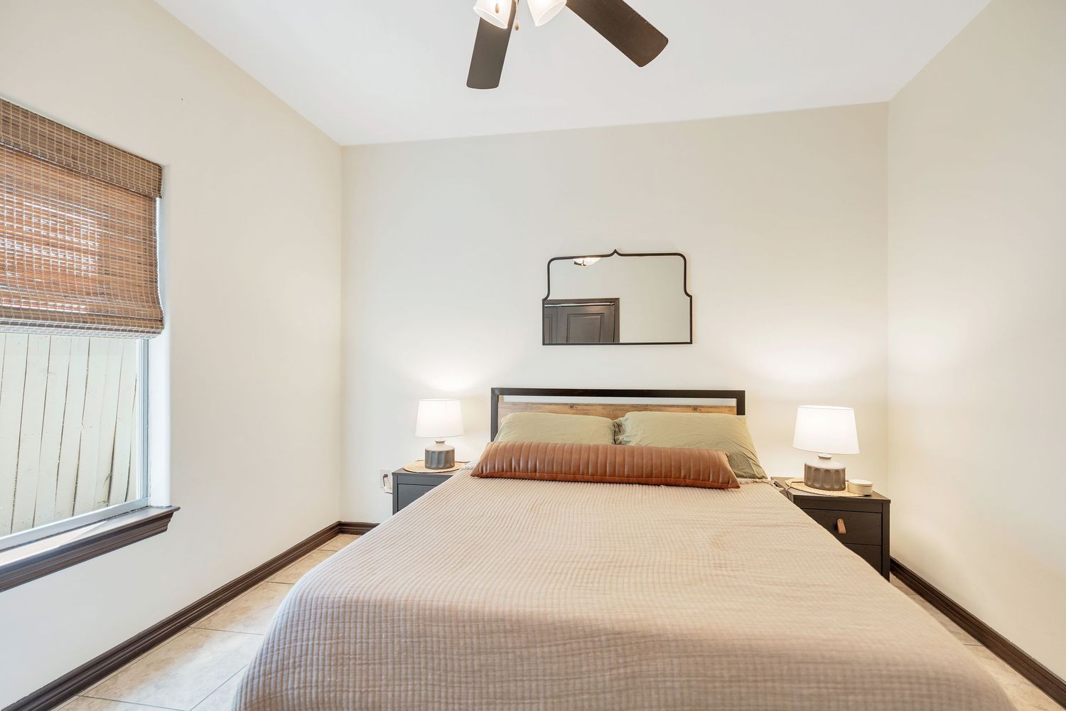 Modern bedroom interior with ceiling fan, wooden trim, and neutral decor showcases a comfortable living space.