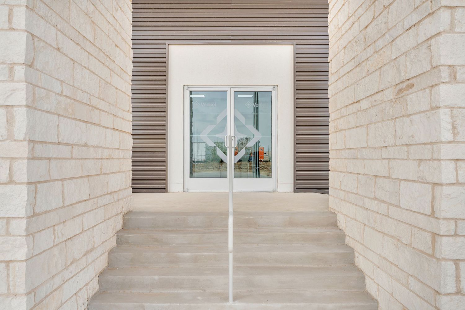 Modern white stone hallway with horizontal metal vents and a window at the end creates a minimalist architectural design.