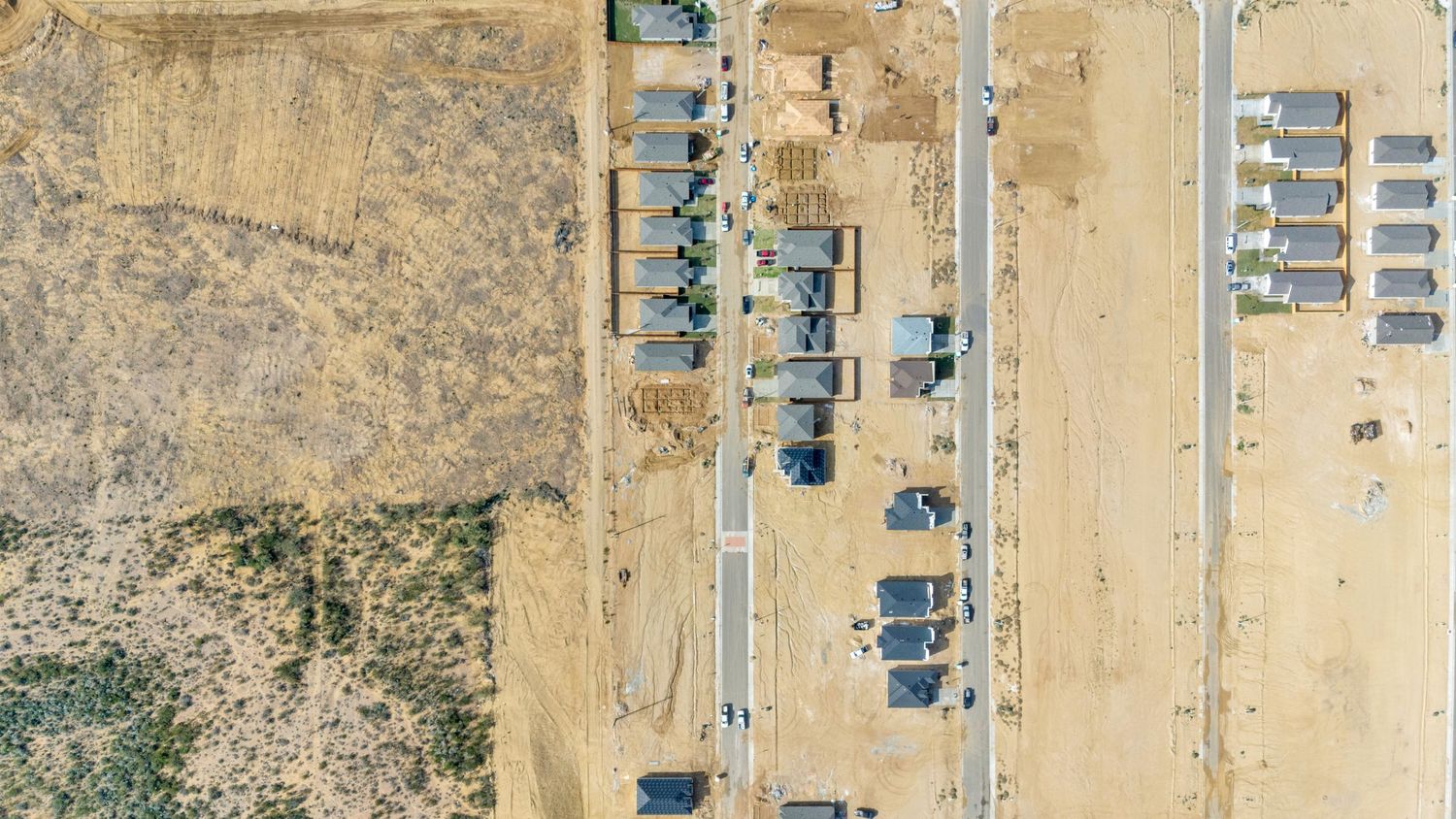 Aerial view of a desert landscape with scattered buildings and roads forming a grid pattern in a sandy terrain.