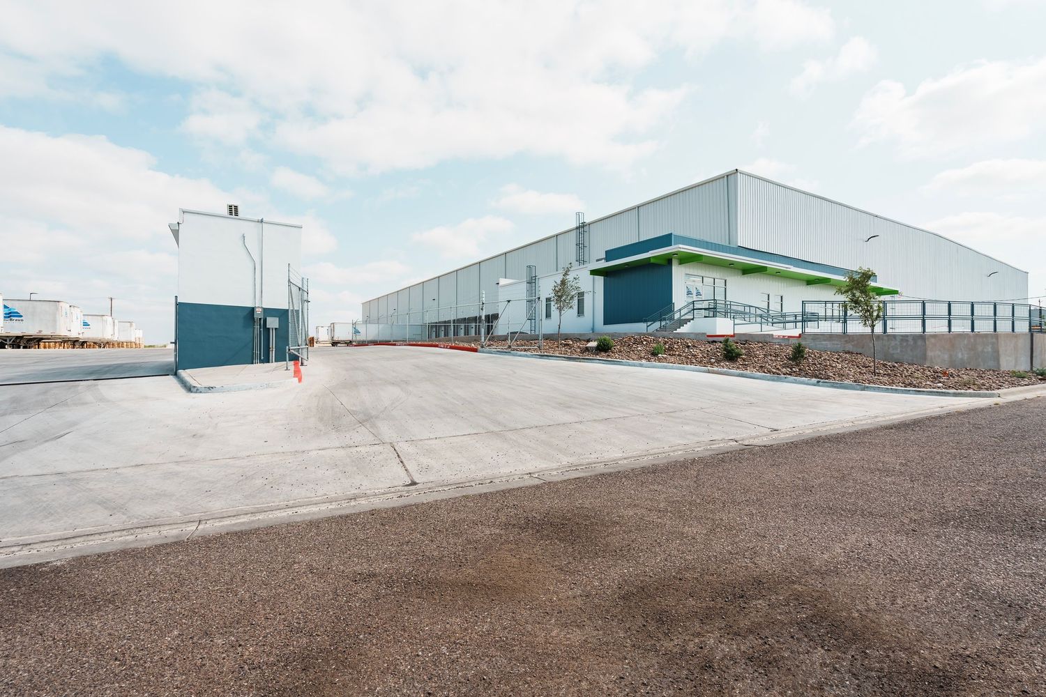 Modern industrial warehouse facility with glass facade and loading docks in a commercial business park.