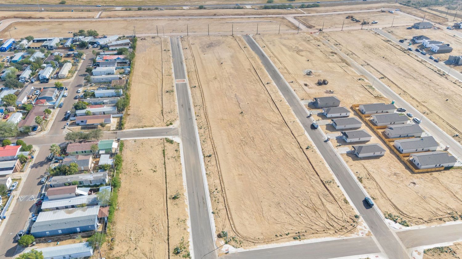 Aerial view of a residential development under construction with roads and housing lots in a desert landscape.