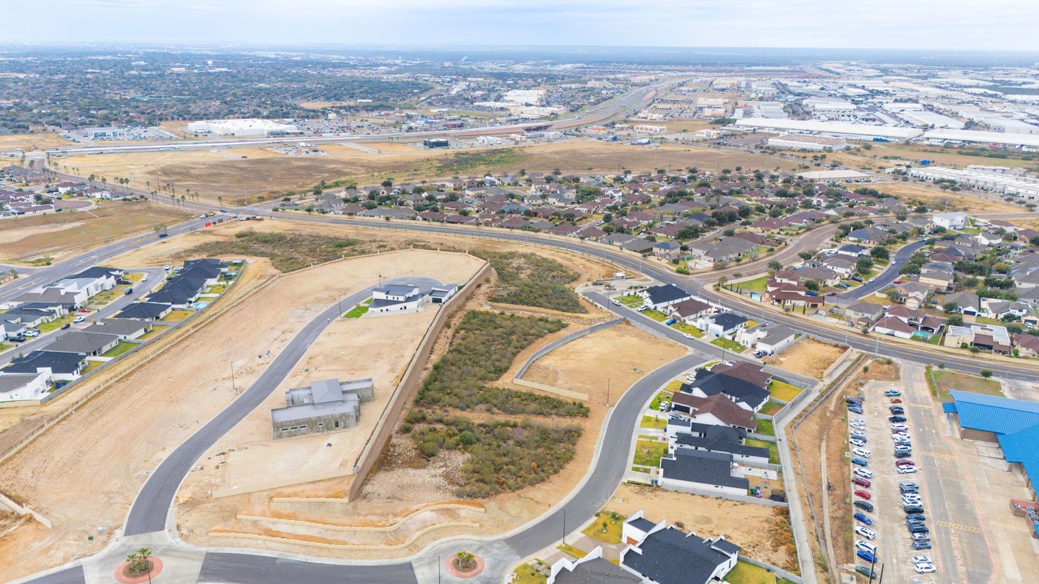 Aerial view of a new residential development with curved roads and construction sites in a suburban area.