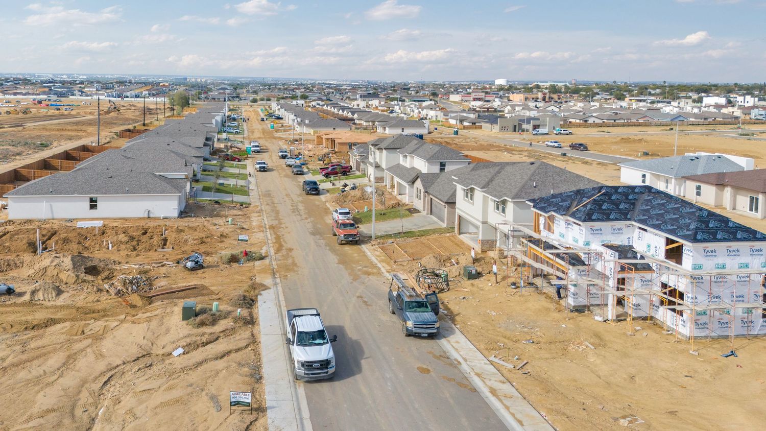 Aerial panoramic view of a residential construction site showing multiple homes in various stages of development.
