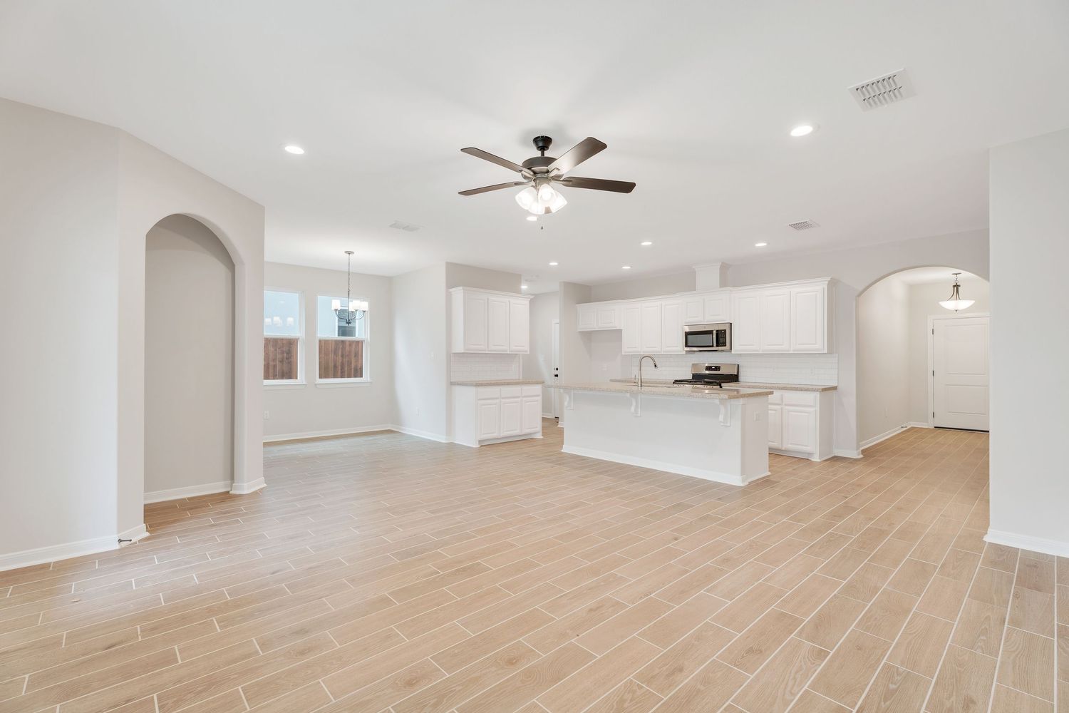 Modern open concept living space with arched doorways, light hardwood floors, and recessed lighting.