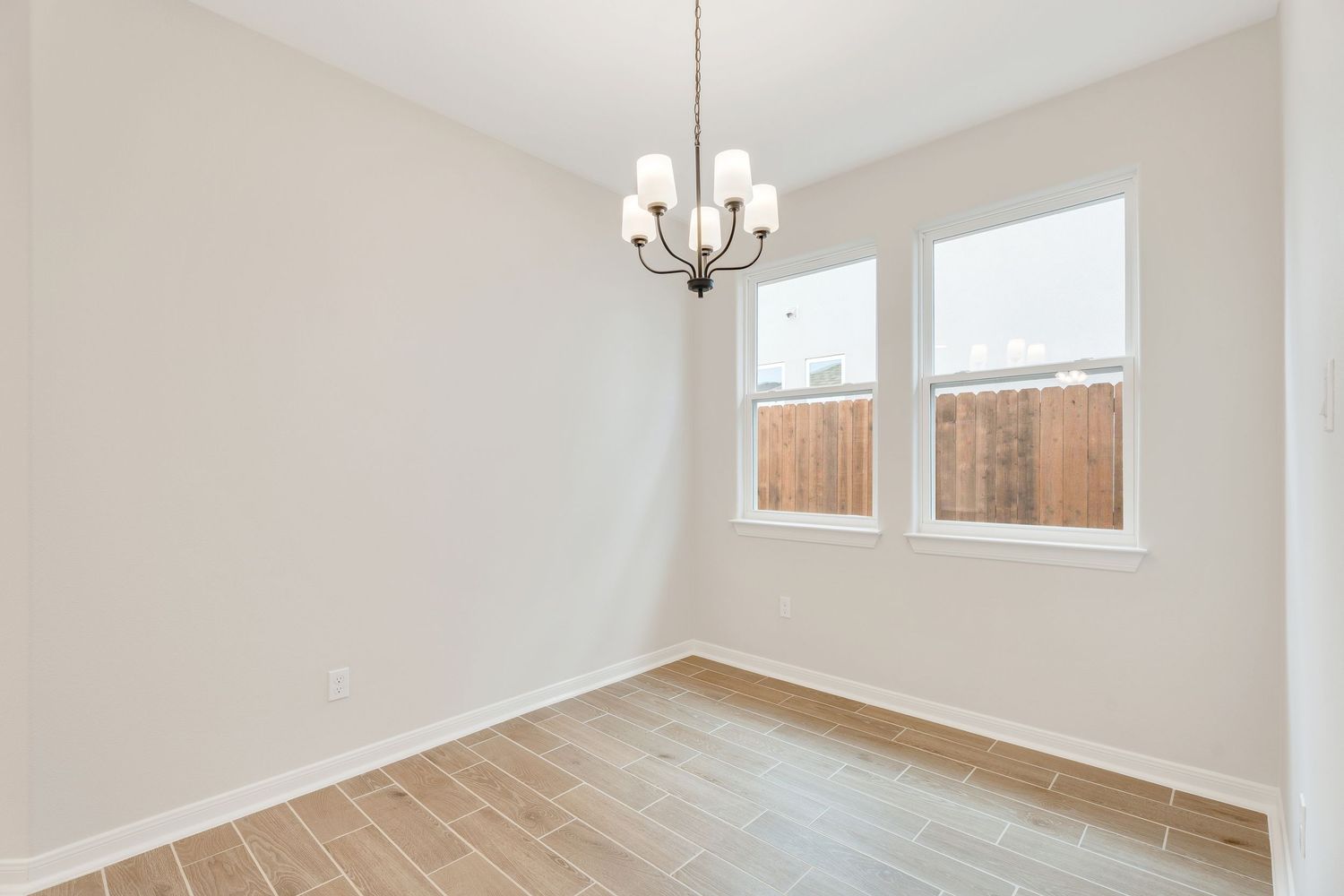 Modern empty room interior with beige walls, hardwood floors, and recessed lighting showcasing open concept living space.