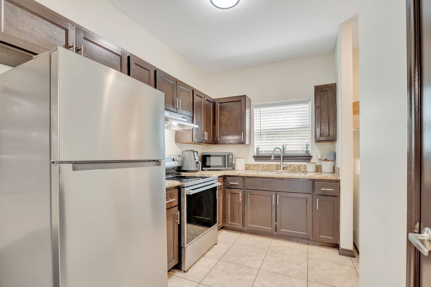 Contemporary kitchen featuring brown cabinets, stainless steel appliances, and open concept layout with ample lighting.