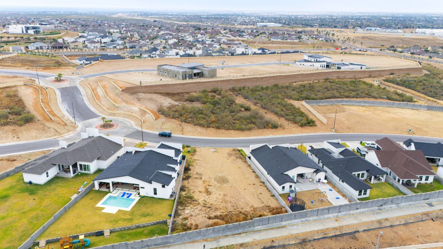 Aerial panoramic view of a suburban housing development with construction sites and roads in a desert landscape.