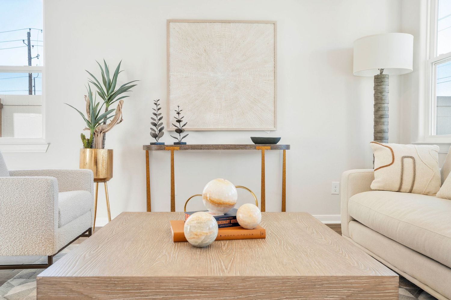 Modern minimalist living room interior with white walls, natural light, and decorative elements on a wooden dining table.