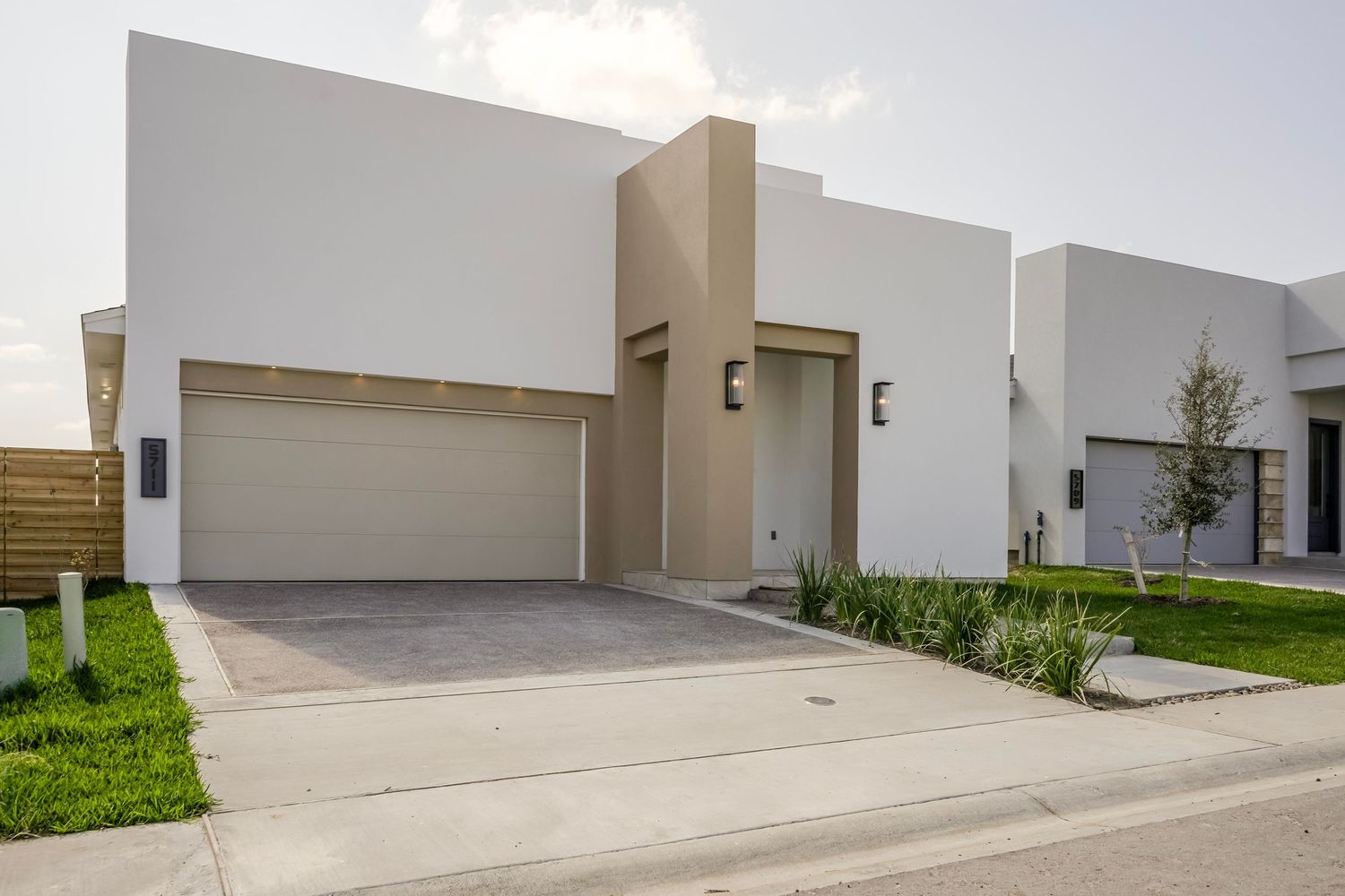Contemporary white house with minimalist design featuring two-car garage and landscaped front yard.