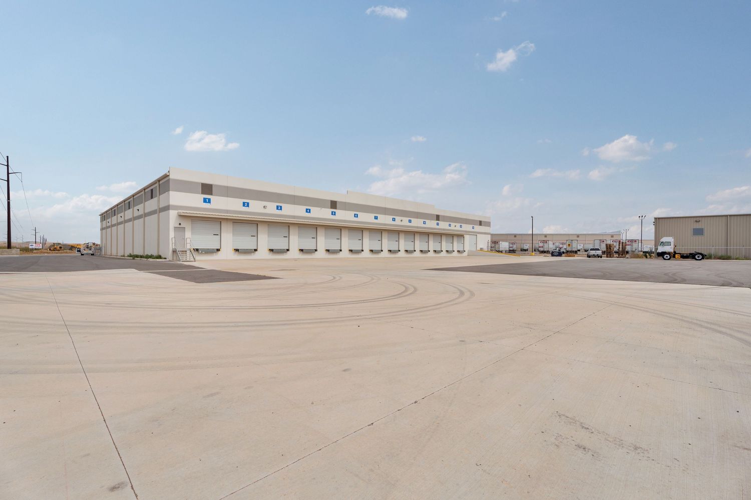 A panoramic view of an industrial facility with warehouses and storage buildings in a desert landscape.