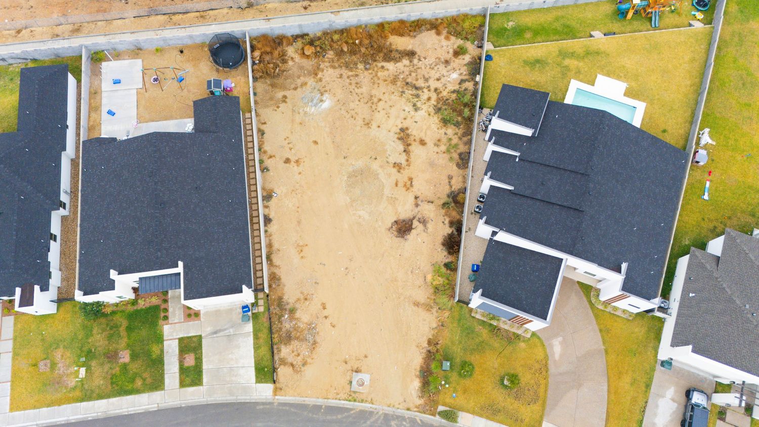Aerial view of a residential neighborhood with houses and construction sites on sandy terrain.