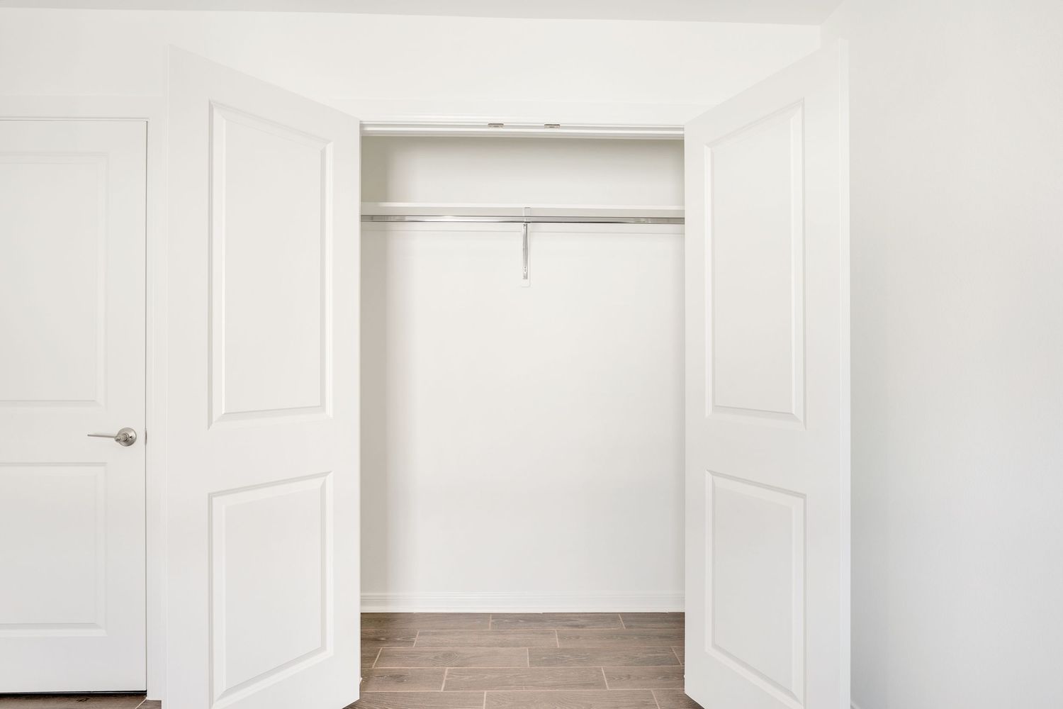 A series of white interior doors and doorways in an empty room with white walls and hardwood flooring.