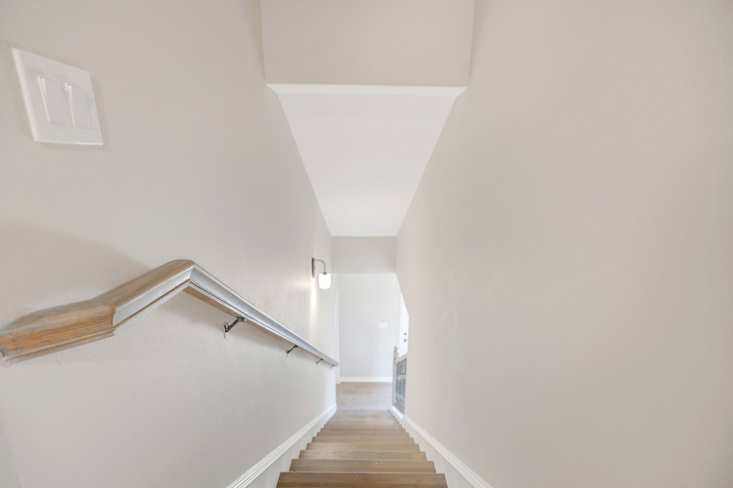 White cathedral ceiling with exposed wooden beams and skylights creates an airy, bright atmosphere in a modern interior.