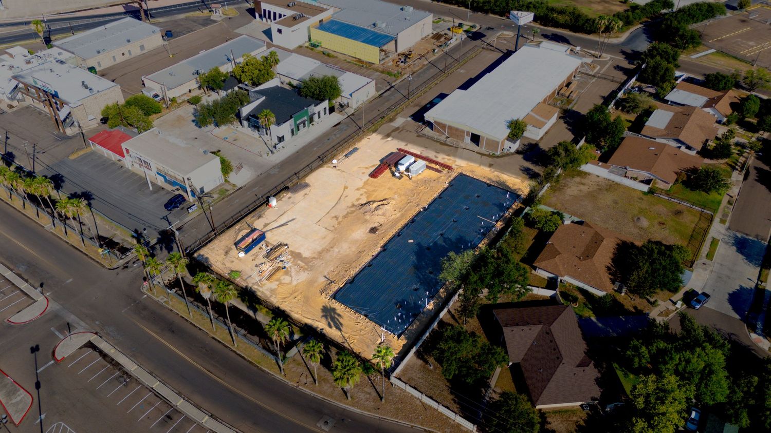 Aerial drone view of suburban neighborhood streets and houses with blue roofs on a sunny day.