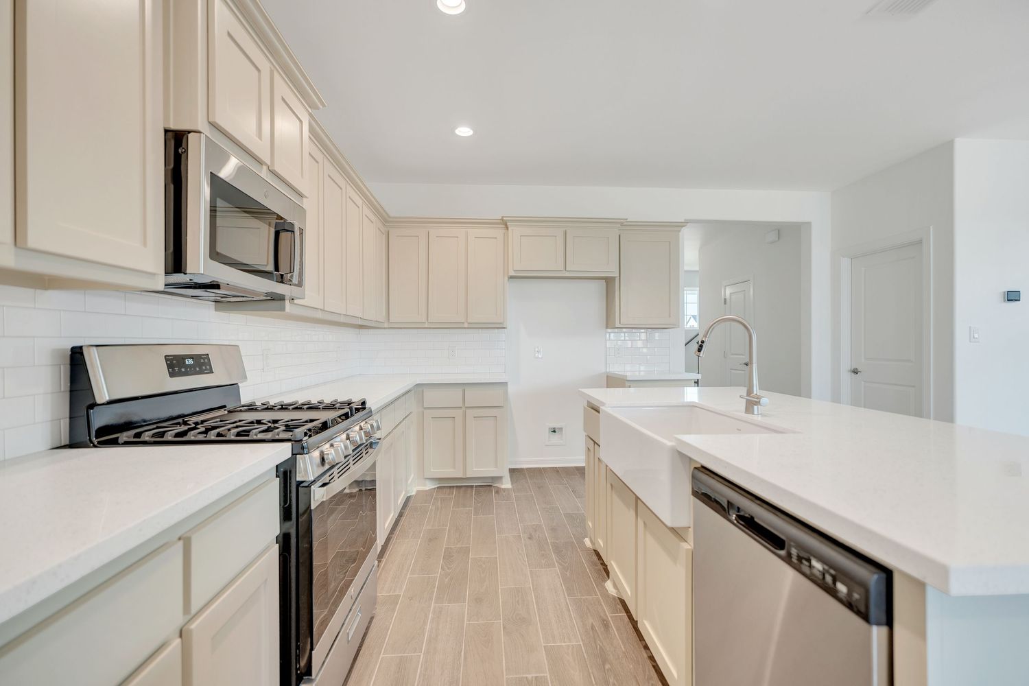 Modern white kitchen with quartz countertops, light cabinets, and stainless steel appliances features a spacious island.