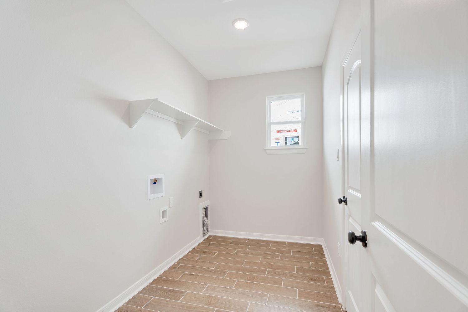 Empty white bedroom with hardwood floors and recessed lighting in modern apartment interior.