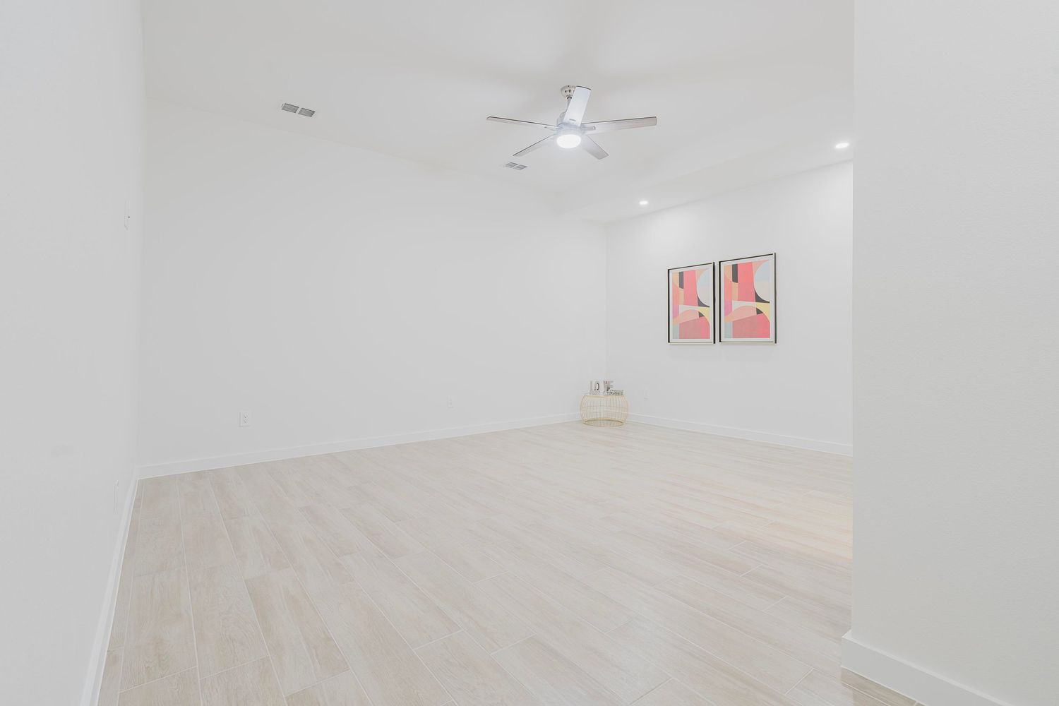 Spacious white room with light wood floors and red wall art.