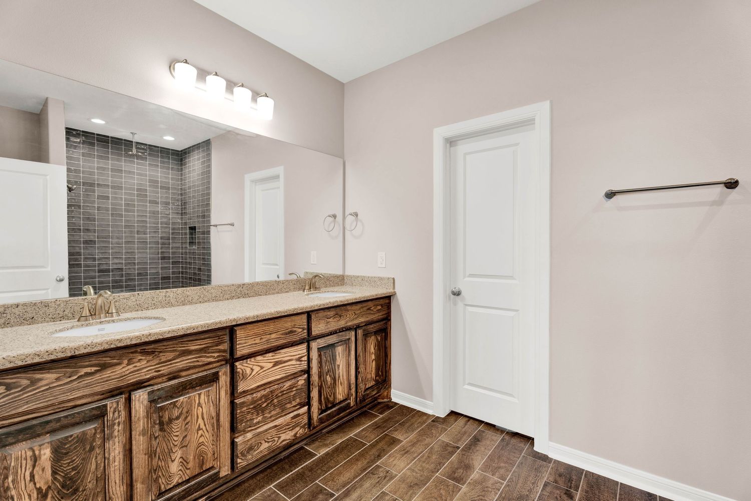 Modern bathroom with rustic wood vanity, dual sinks, large mirror, and tiled walk-in shower.