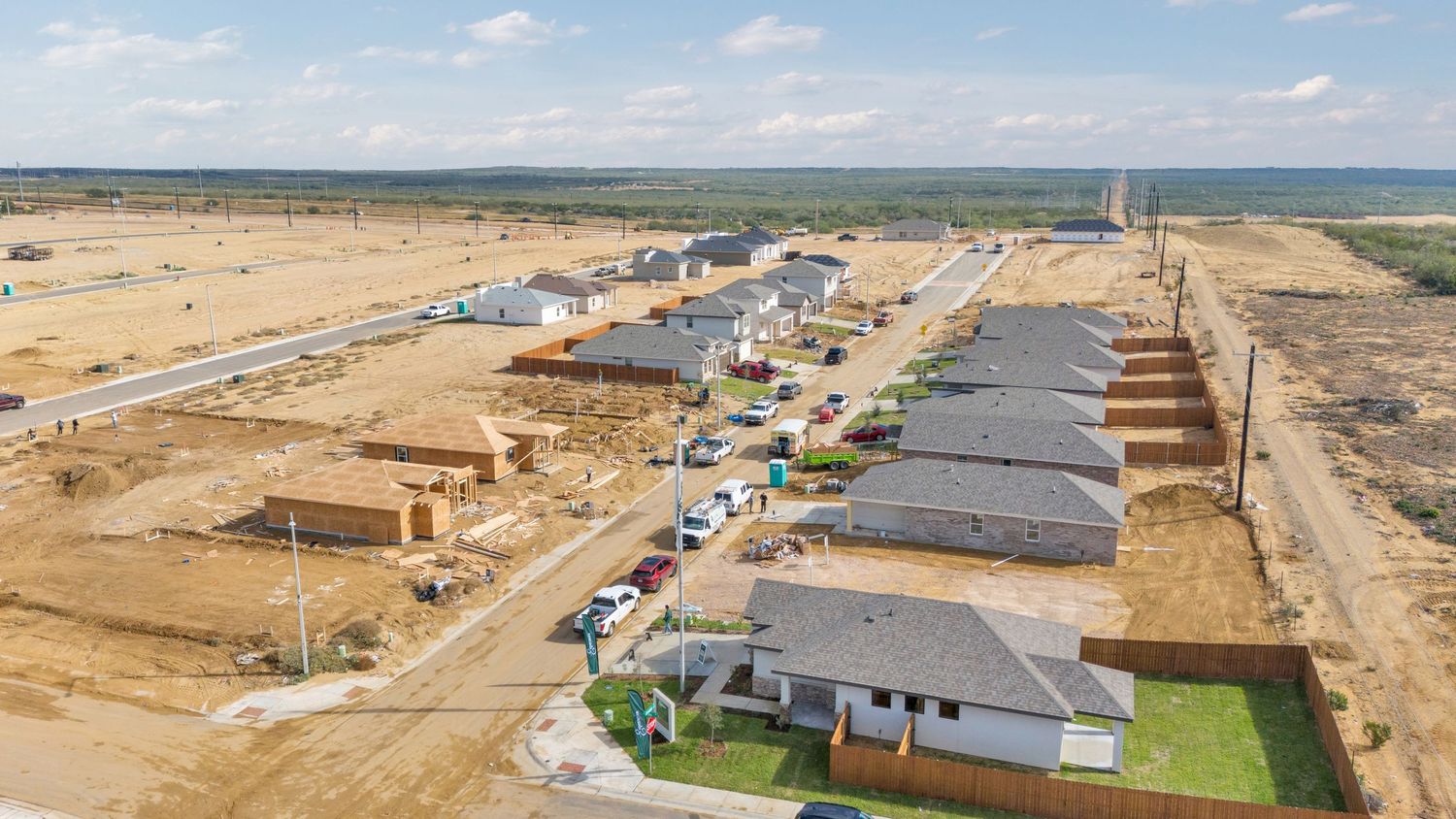 Aerial panoramic view of new residential construction development with homes in various stages of completion in desert landscape.