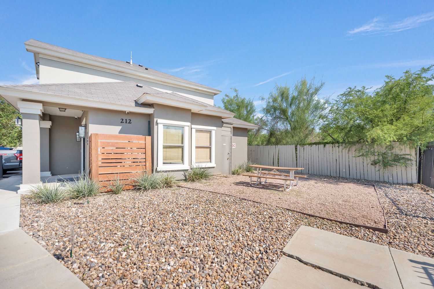 Modern desert home with xeriscaped front yard featuring gravel landscaping and wooden bench seating.