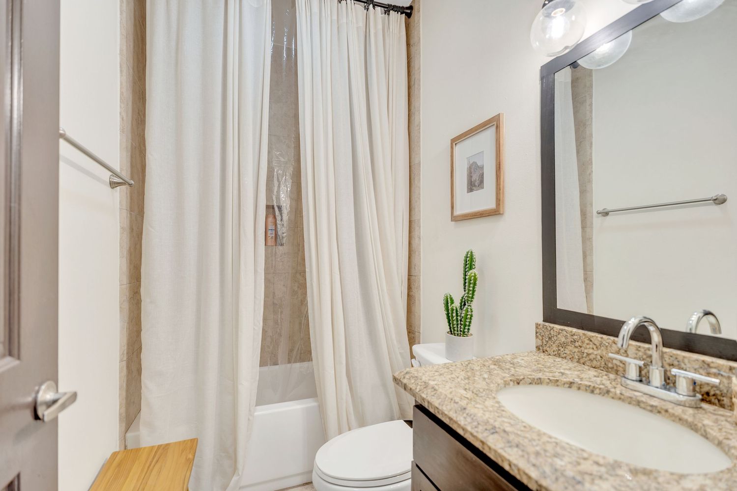Bright bathroom interior with white curtains, modern fixtures, and beige countertop vanity.