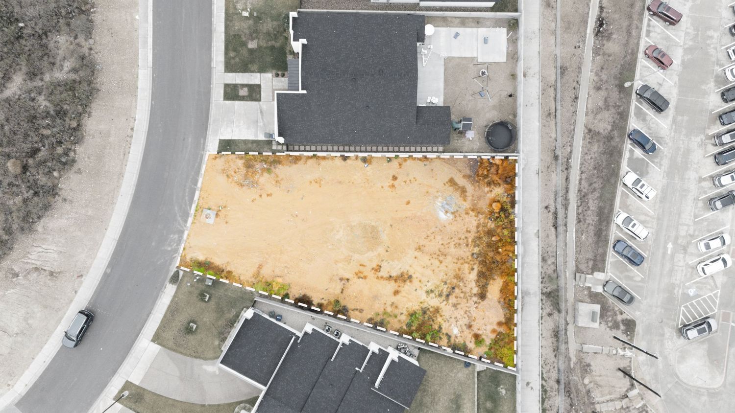 Aerial view of a curved road intersection with buildings and parking lots visible from above.