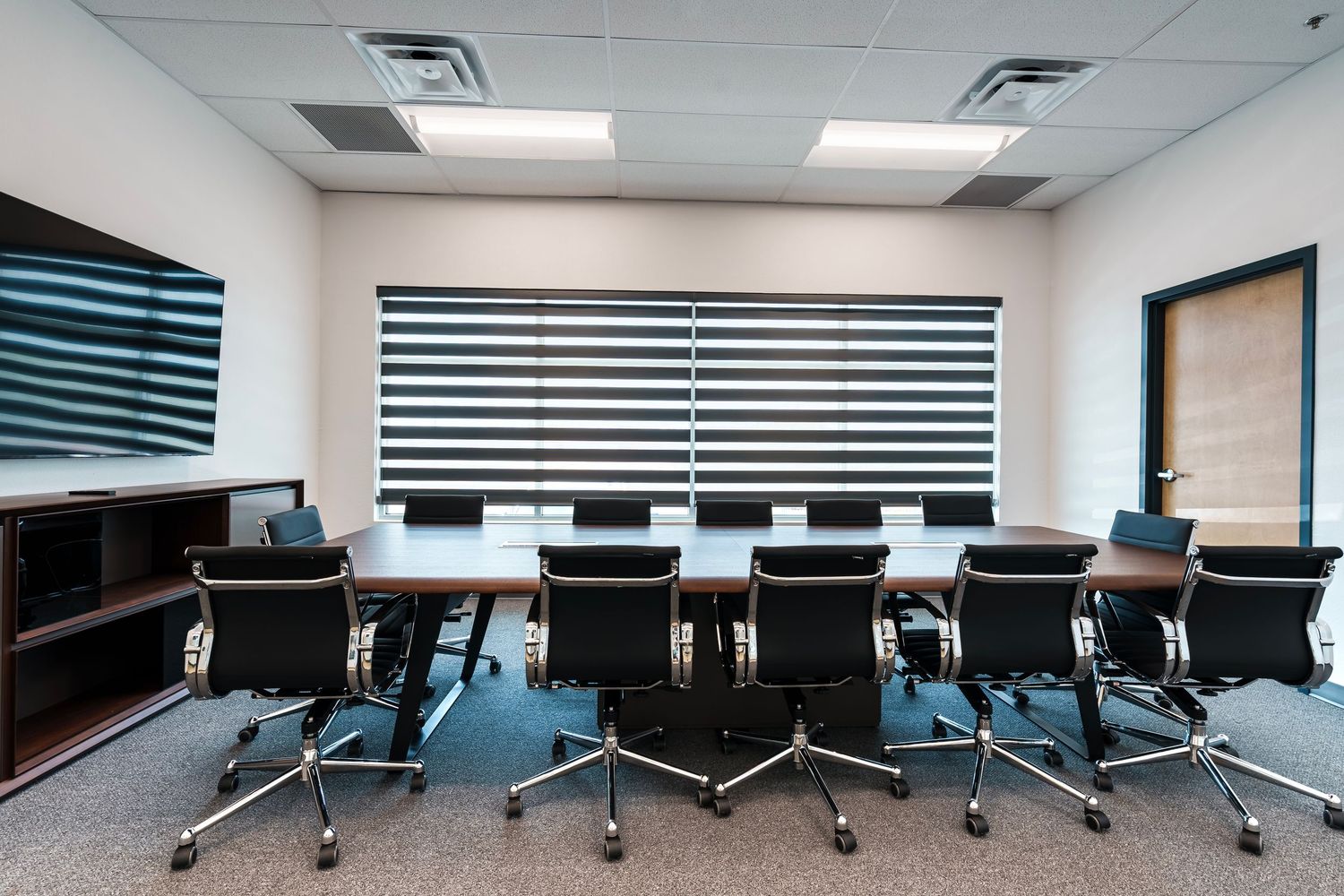 Modern conference room with blue office chairs and striped window blinds in a minimalist corporate setting.