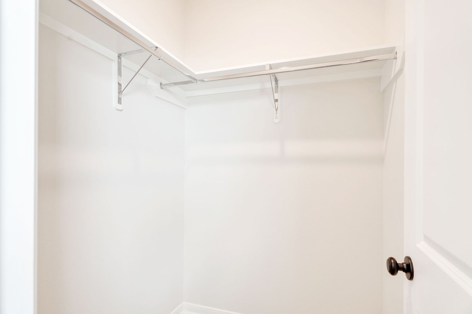 White modern bathroom interior with subway tile walls, floating vanity, and round mirror mounted above the sink.