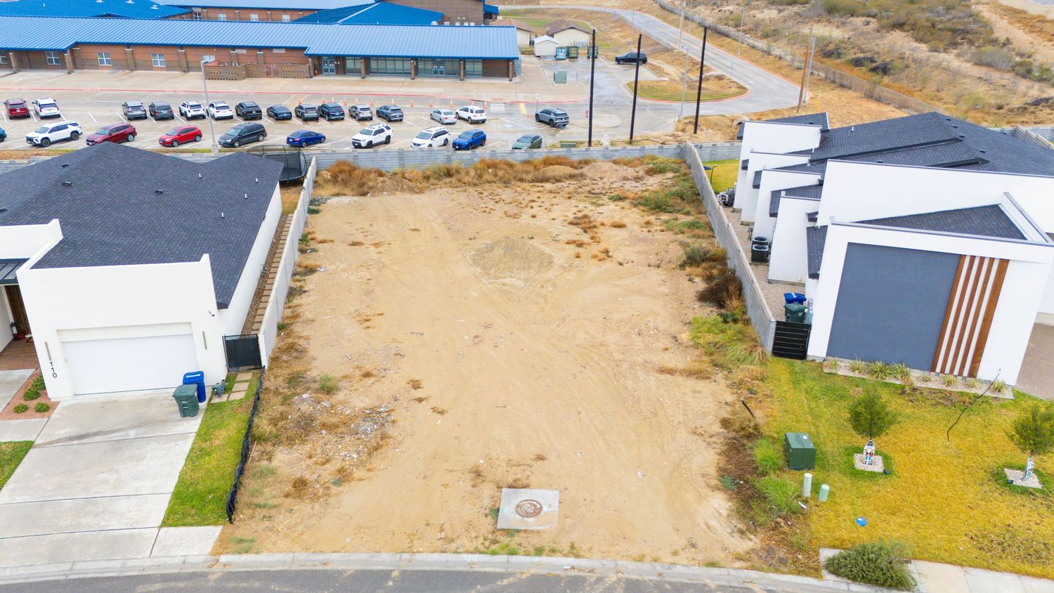 Wide aerial shot of commercial buildings and parking lots in a developing industrial area with desert surroundings.