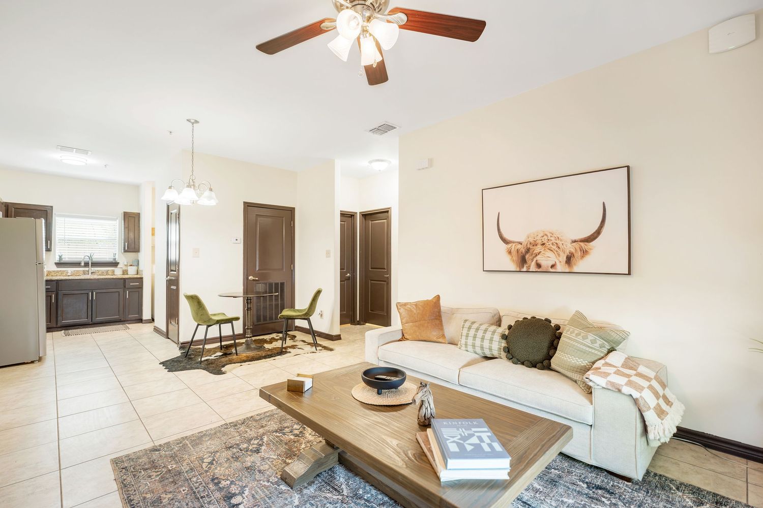 Contemporary living room with ceiling fan, plush furniture, and modern decor.