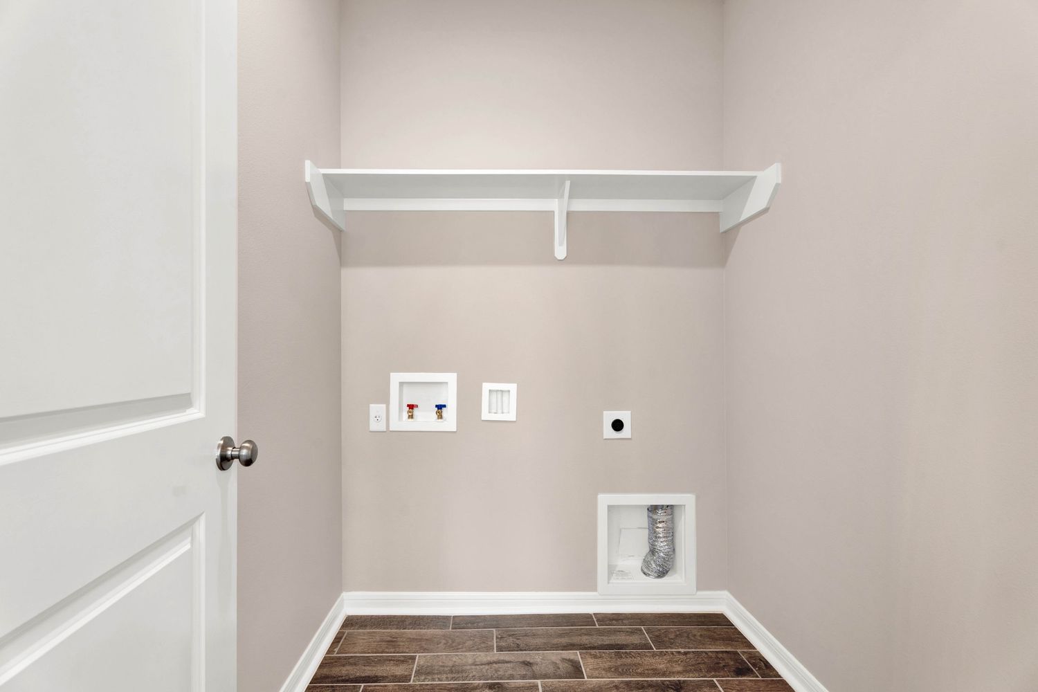 Laundry room with white shelf, washer and dryer hookups, gas dryer connection, and dark wood-look tile flooring.
