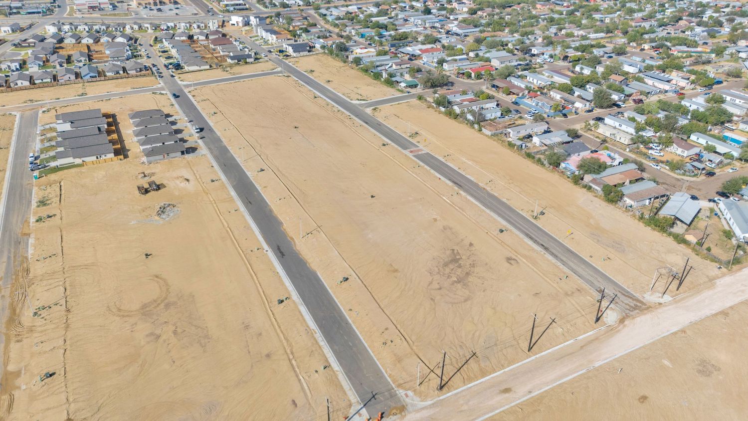 Aerial view of a large residential development site showing new streets and housing lots in a desert landscape.