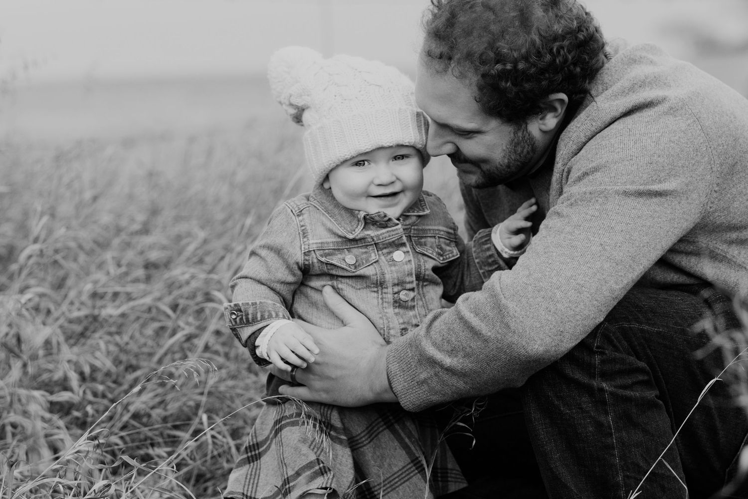 A tender black and white moment shared between parent and child in an outdoor field setting.