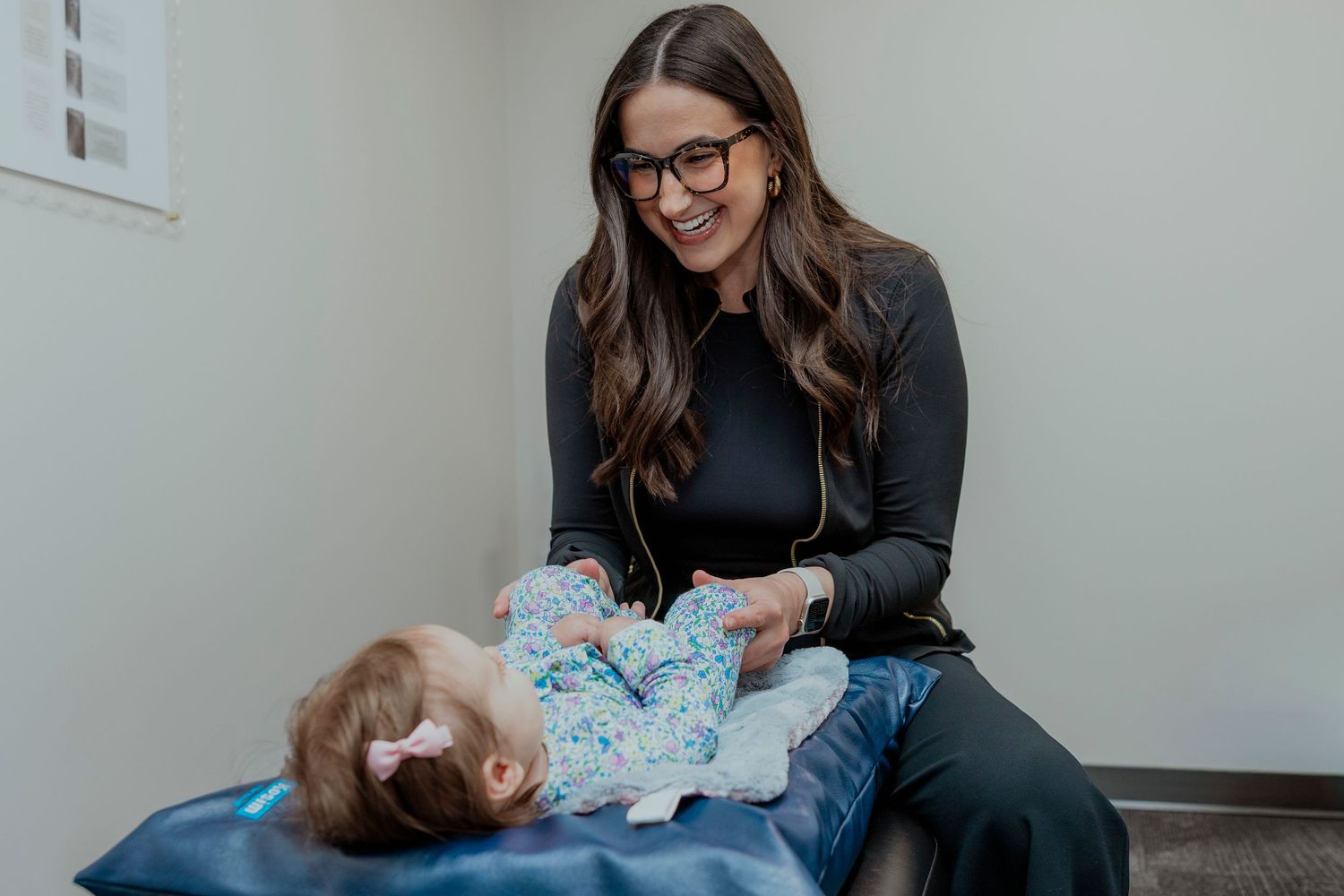 A chiropractor performs a gentle spinal adjustment on a young patient lying on a treatment table. Saskatoon business branding photographer