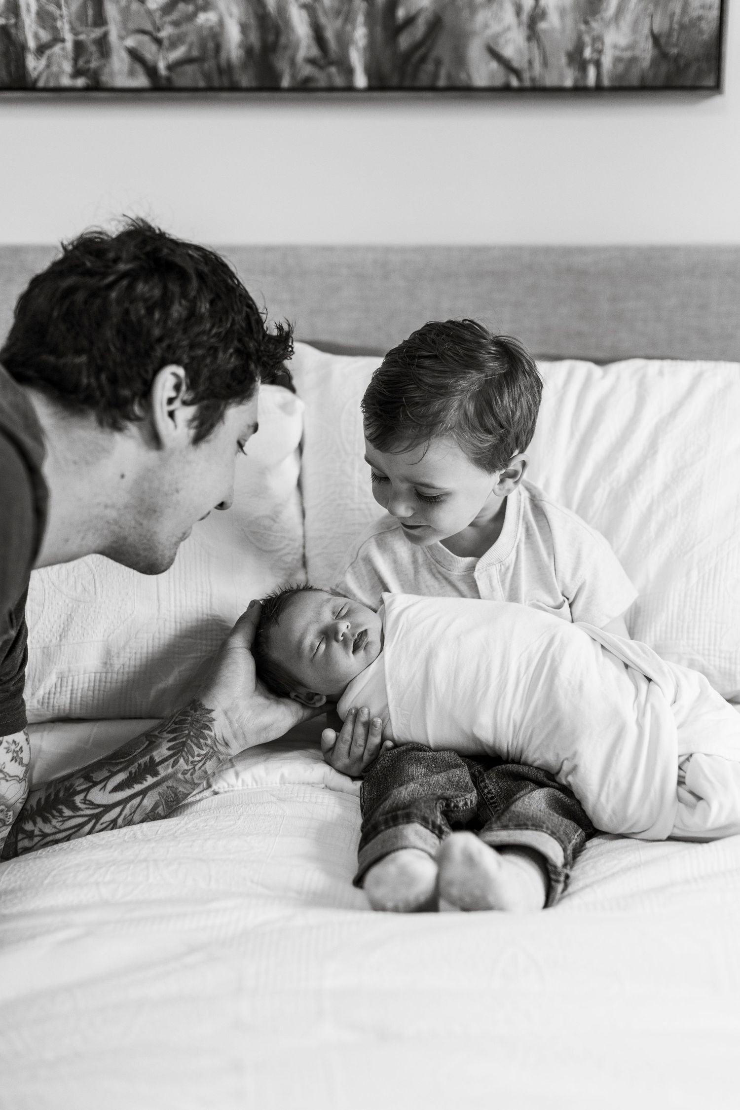 A tender black and white family moment shows three people sharing a quiet, intimate moment together on a couch.