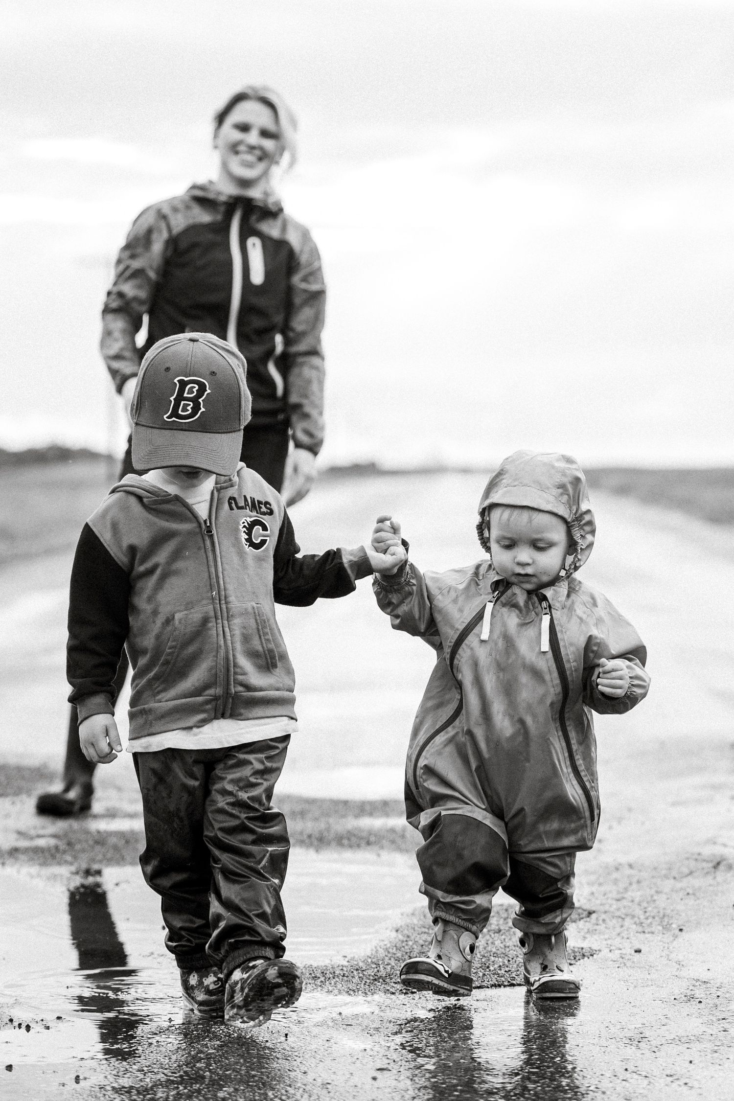 Black and white image of rainy day walk featuring puddle splashing and matching outfits.