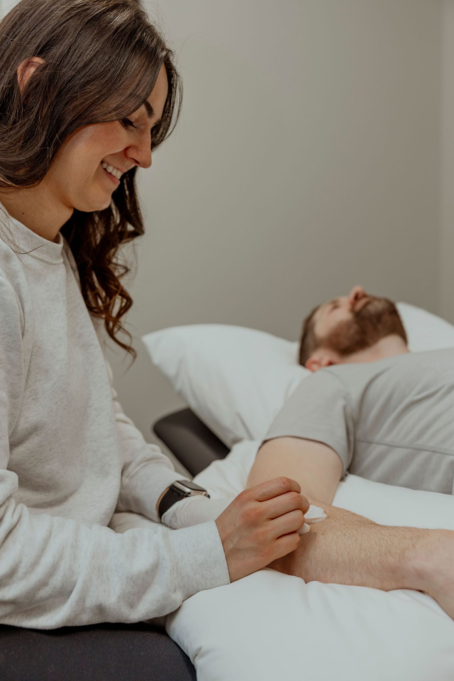 Physical therapist in white sweater performs therapeutic massage treatment on patient.  Saskatchewan business branding content shoot.