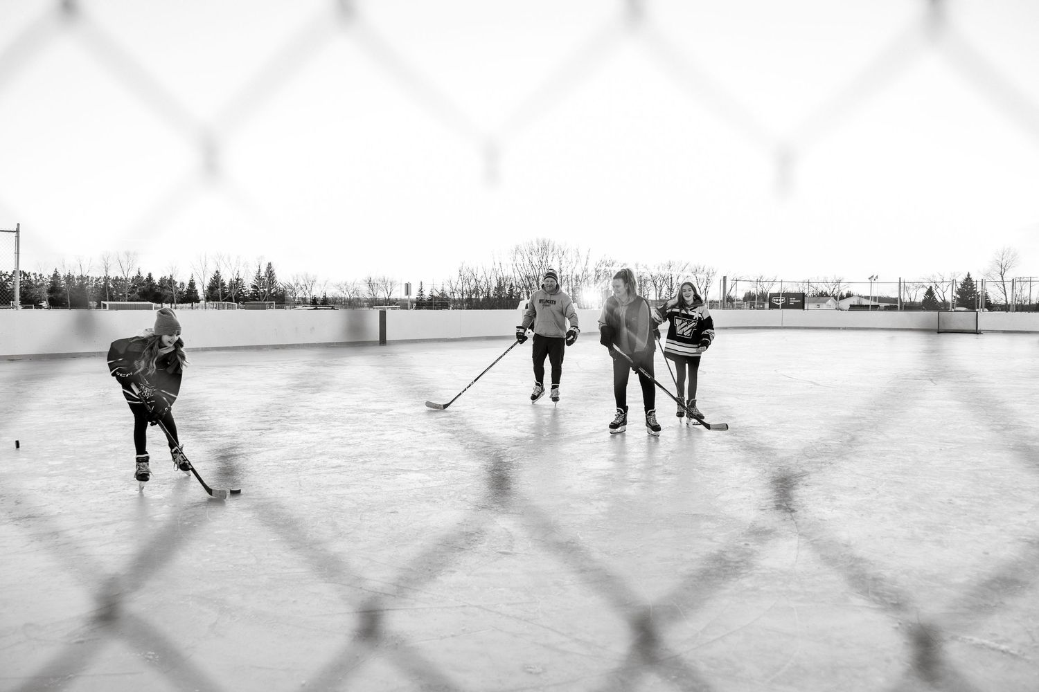 People playing hockey on an outdoor rink in a vintage black and white photograph. Rink photography session Saskatchewan hockey