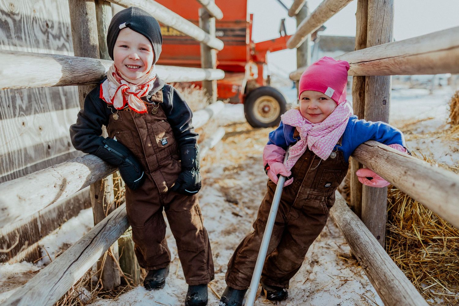 Two children in brown overalls and winter hats help with farm chores.  Lifestyle session, life captured, prairie photographer, saskatchewan